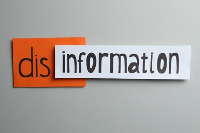 Photo of Word DISINFORMATION made with paper pieces on light grey background, flat lay