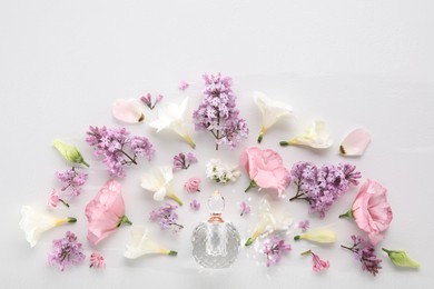 Photo of Luxury perfume and floral decor on white background, flat lay