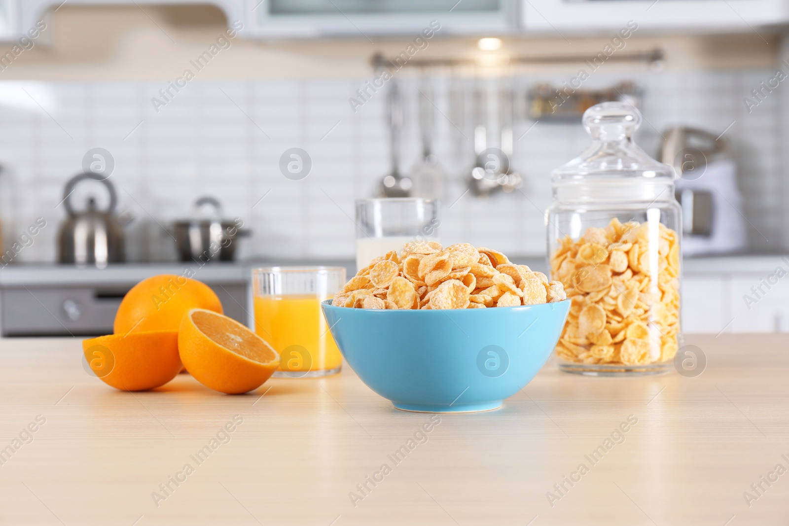 Photo of Cornflakes with glasses of juice and milk on kitchen table