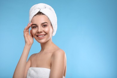 Photo of Happy young woman with towel on head against light blue background, space for text. Washing hair