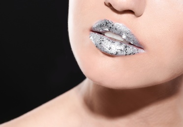 Beautiful young model with silver lips makeup on black background