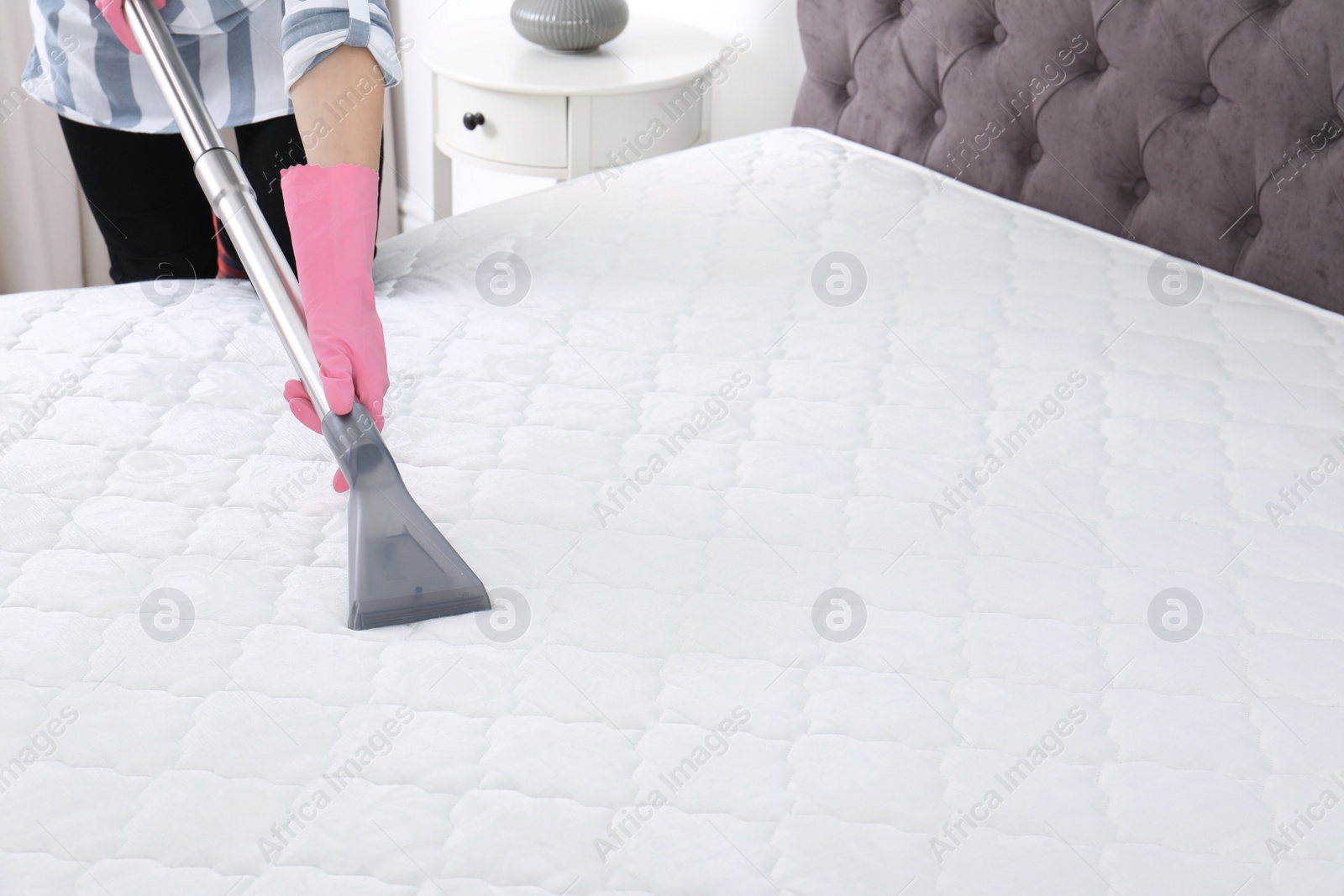 Photo of Woman disinfecting mattress with vacuum cleaner, closeup. Space for text