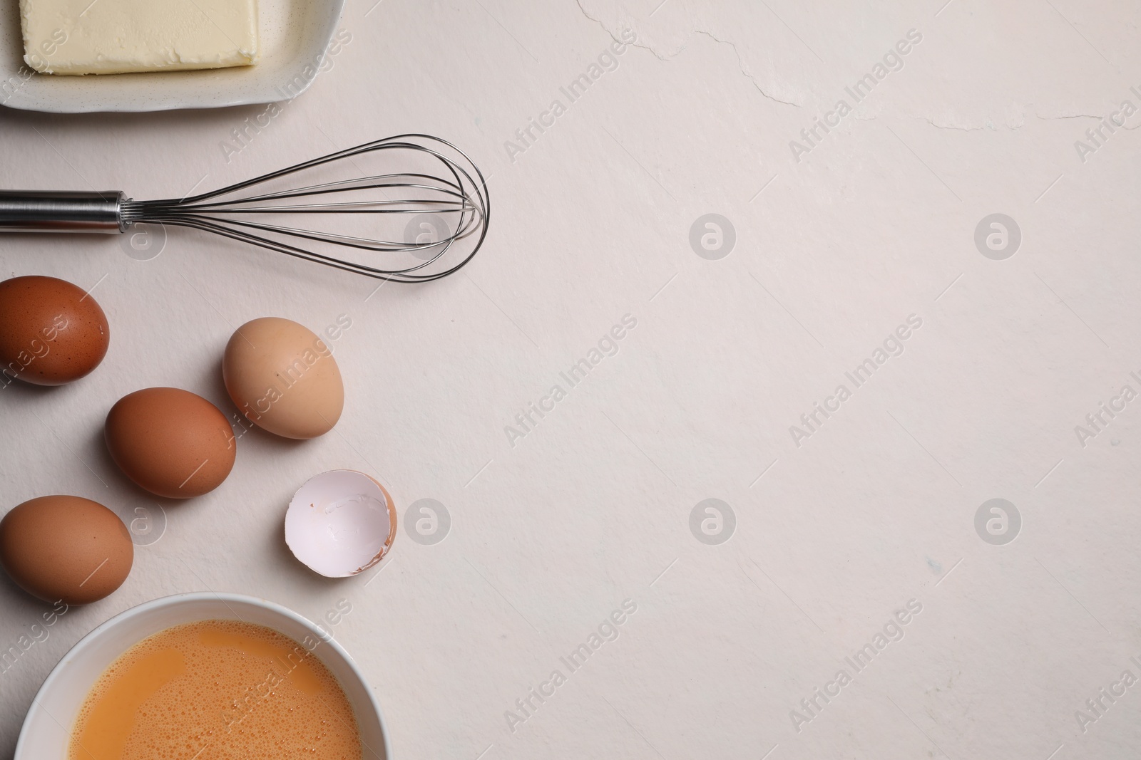 Photo of Flat lay composition with whisk and dough ingredients on light table. Space for text