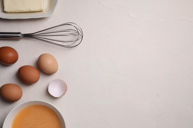 Flat lay composition with whisk and dough ingredients on light table. Space for text