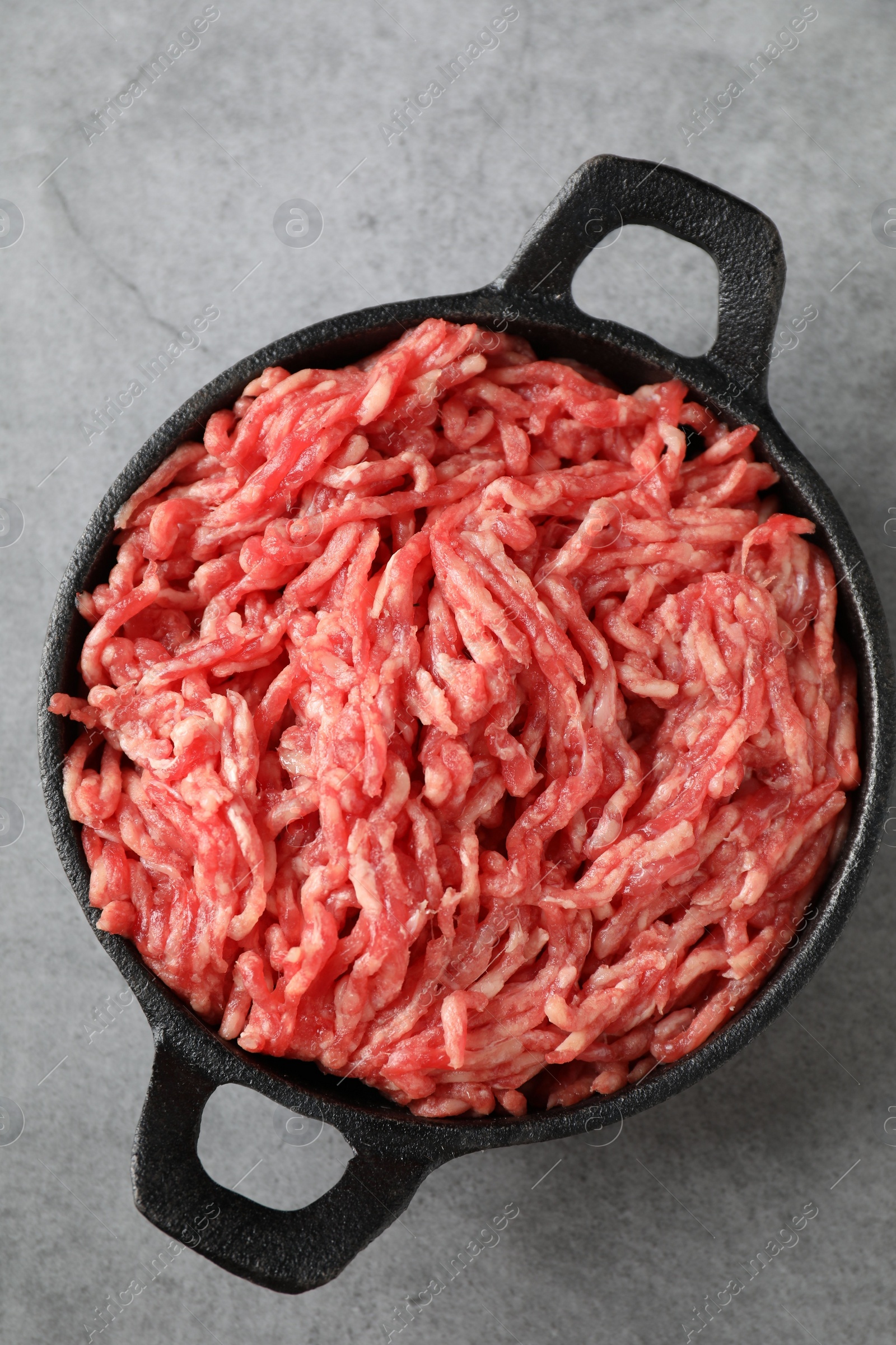 Photo of Raw ground meat in bowl on grey table, top view