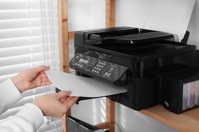 Photo of Woman loading paper into printer on shelf indoors, closeup