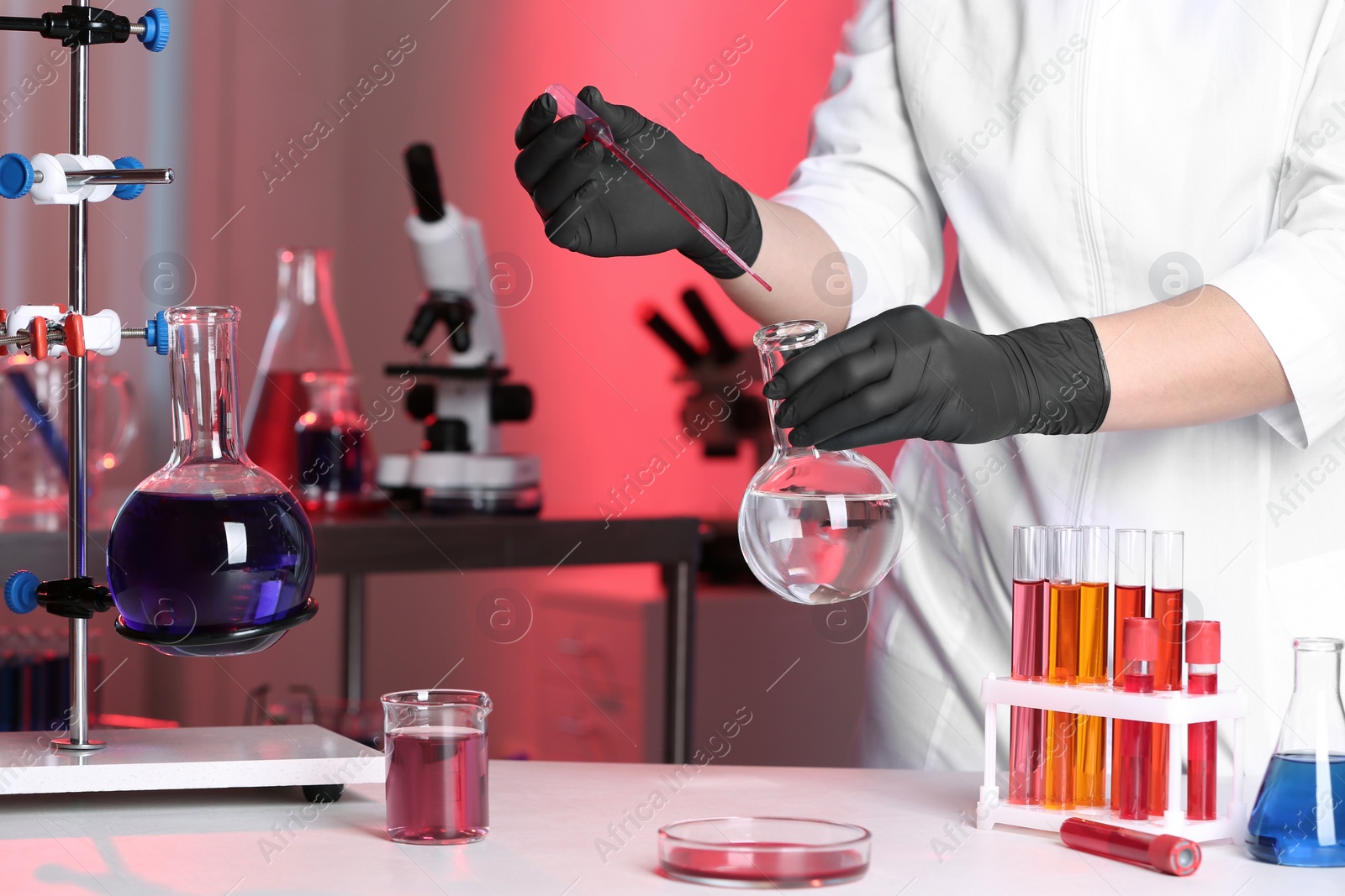 Photo of Scientist pouring reagent into flask at table in chemistry laboratory