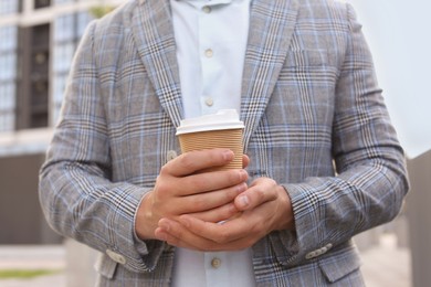 Photo of Coffee to go. Man with paper cup of drink outdoors, closeup