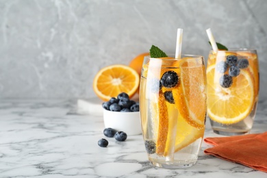 Photo of Delicious orange lemonade with soda water, mint and blueberries on white marble table, space for text. Fresh summer cocktail