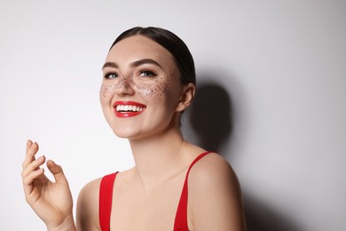 Photo of Happy woman with glitter freckles on light background
