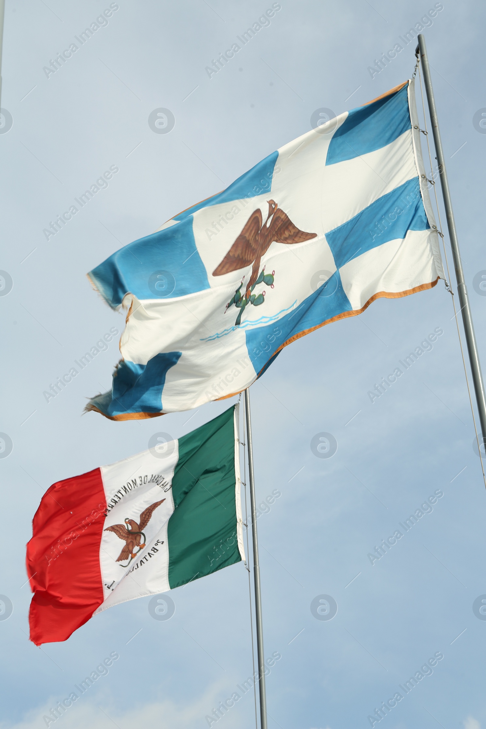 Photo of Mexico flags fluttering against blue sky on sunny day, low angle view