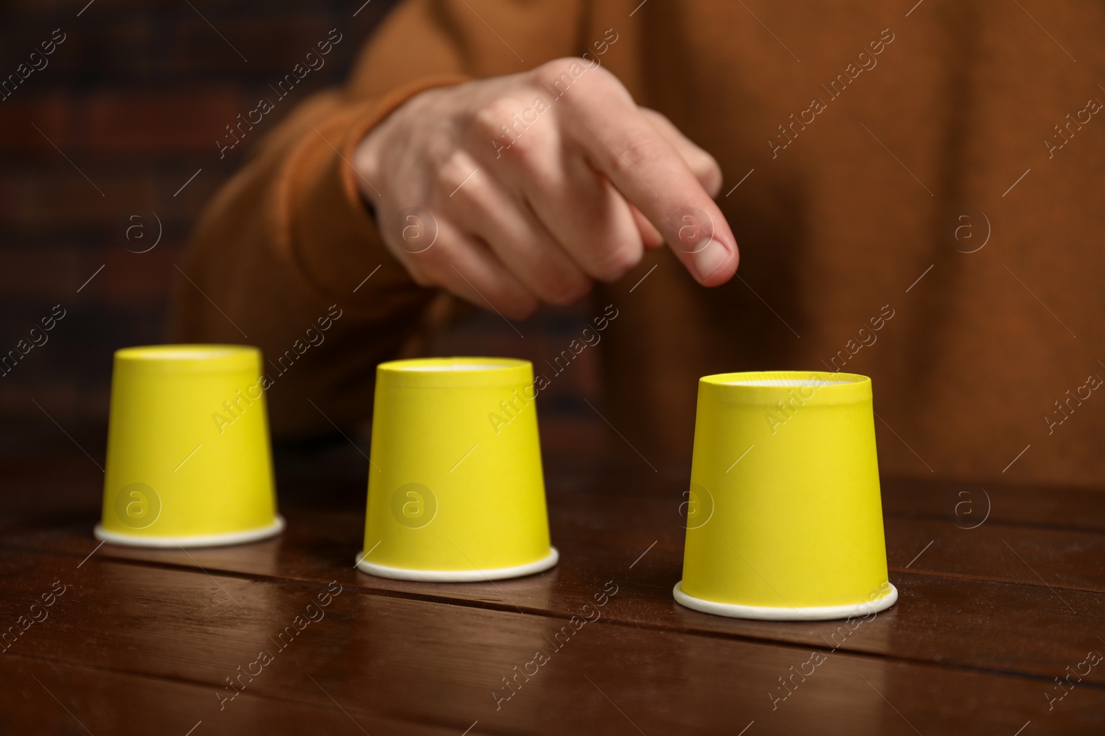 Photo of Man playing shell game at wooden table, closeup