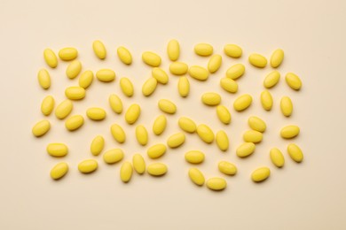 Photo of Many tasty dragee candies on yellow background, flat lay