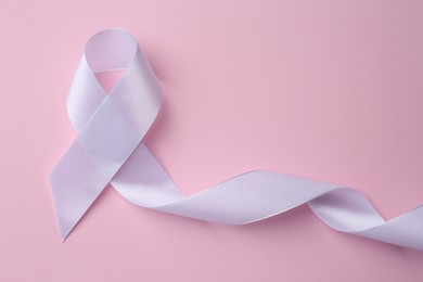 Photo of White awareness ribbon on pink background, top view. Space for text