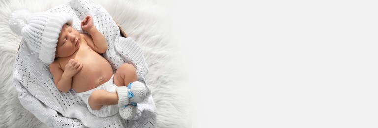 Image of Cute newborn baby in warm hat and socks sleeping on knitted blanket, top view with space for text. Banner design