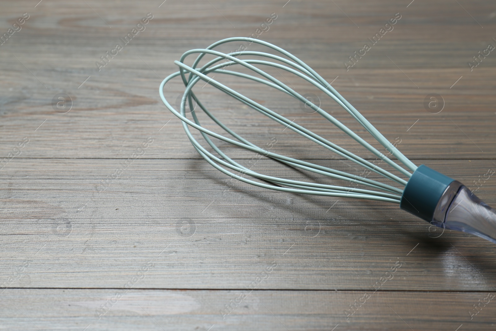Photo of One whisk on wooden table, closeup. Space for text