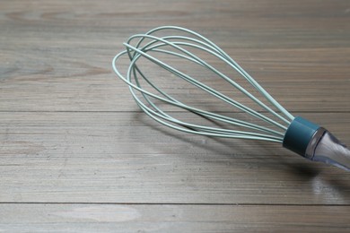 Photo of One whisk on wooden table, closeup. Space for text