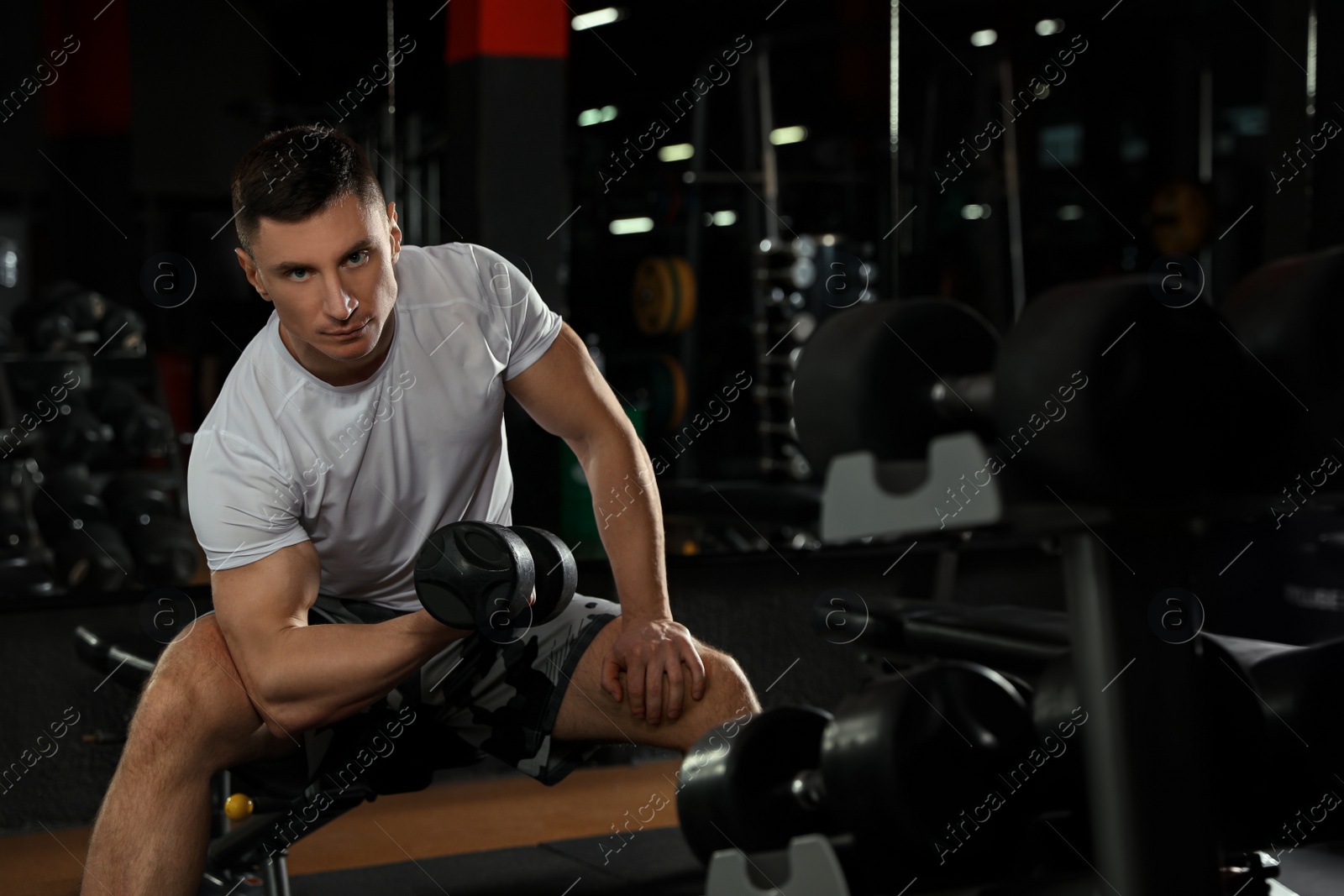 Photo of Man working out with dumbbell in modern gym