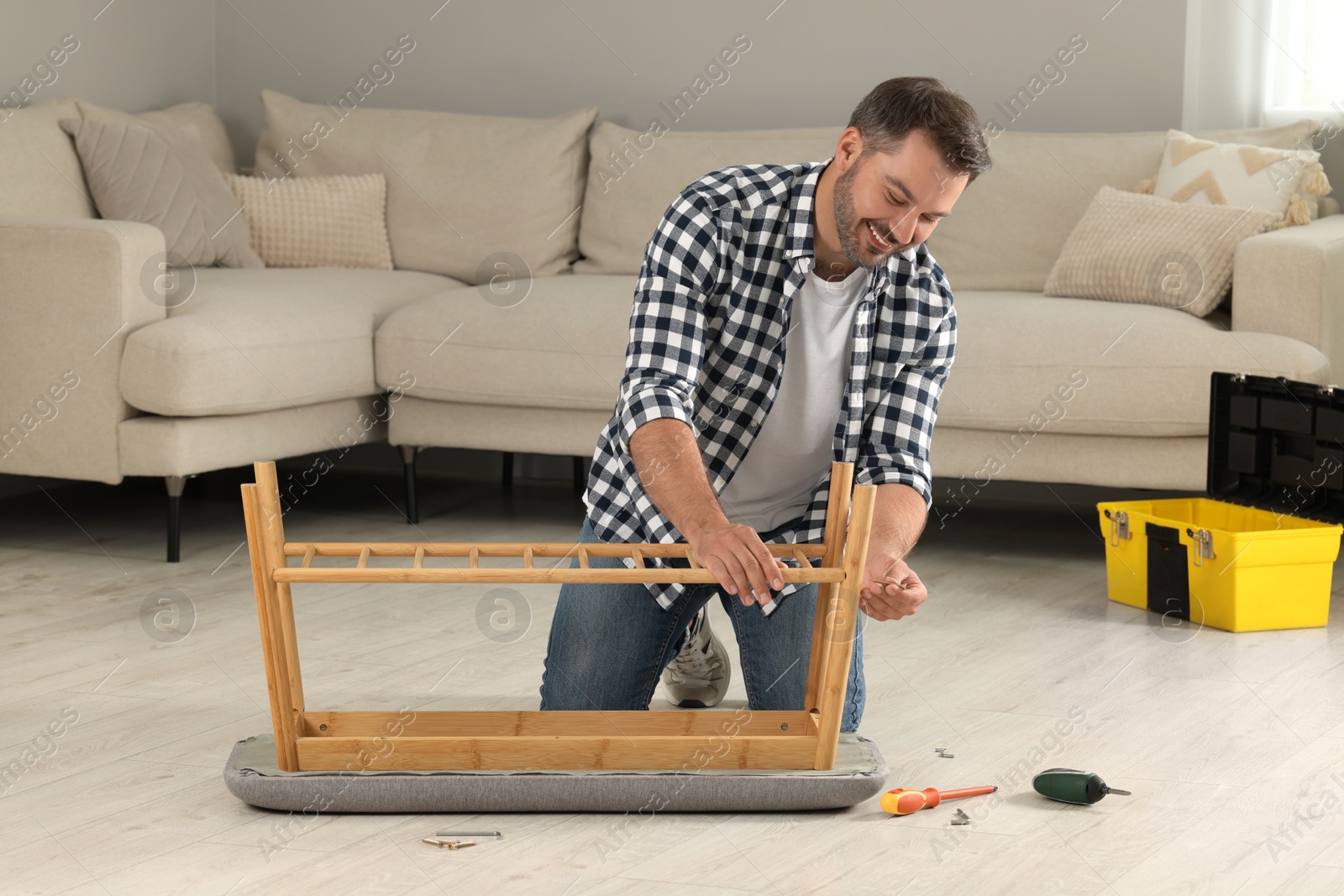 Photo of Man assembling shoe storage bench on floor at home