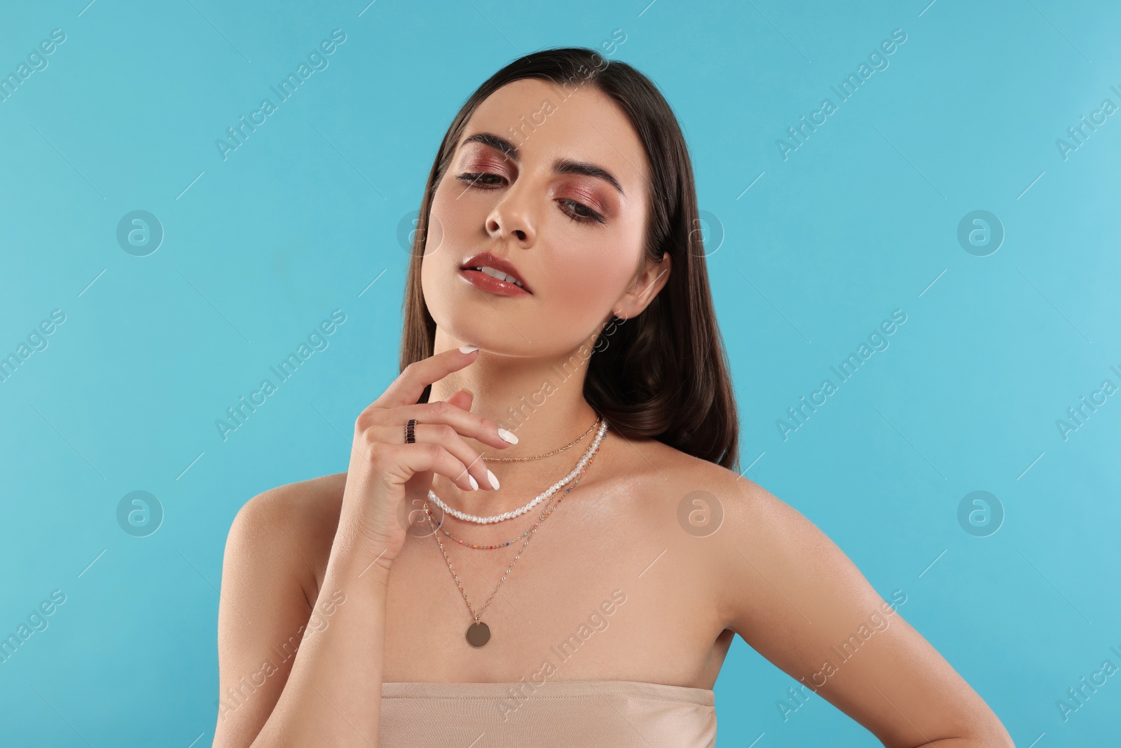 Photo of Beautiful woman with elegant jewelry on light blue background