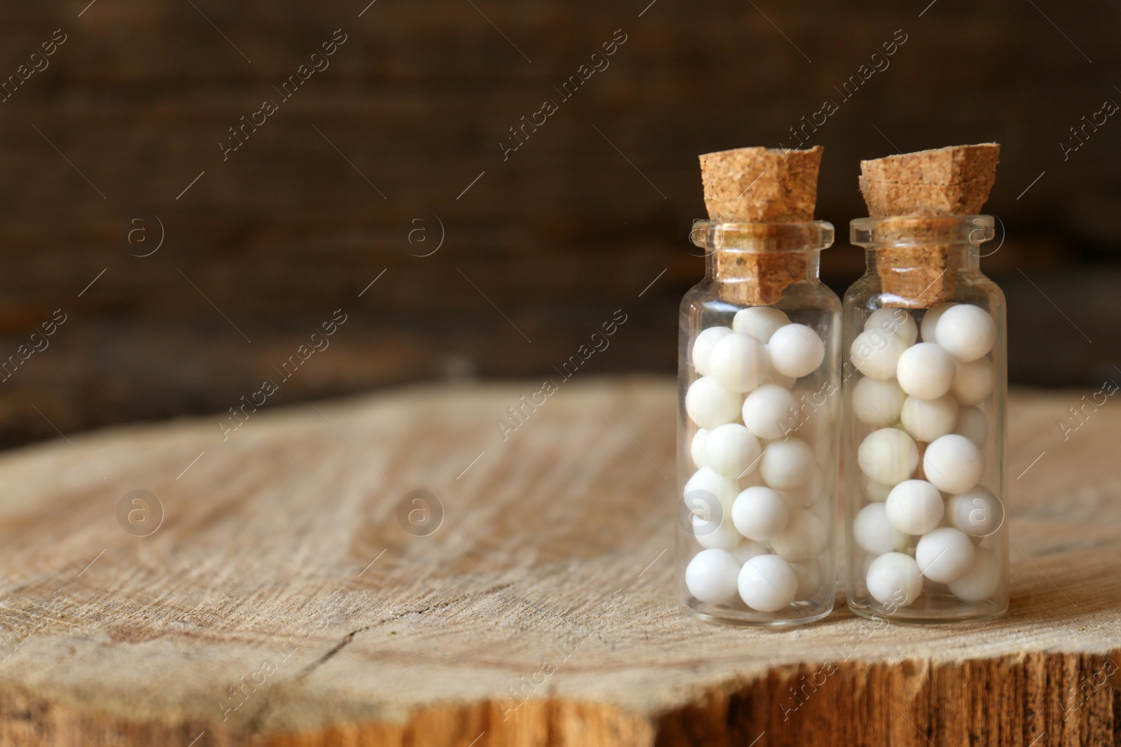 Photo of Bottles with homeopathic remedy on wooden stump. Space for text