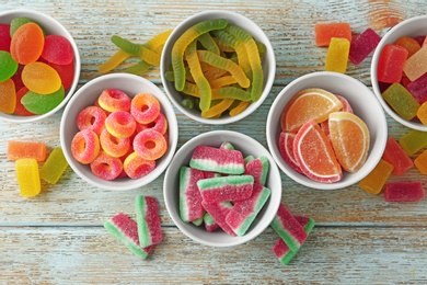 Photo of Flat lay composition with bowls of different jelly candies on wooden background