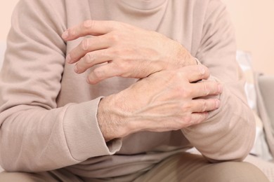 Senior man suffering from pain in his wrist at home, closeup. Arthritis symptoms