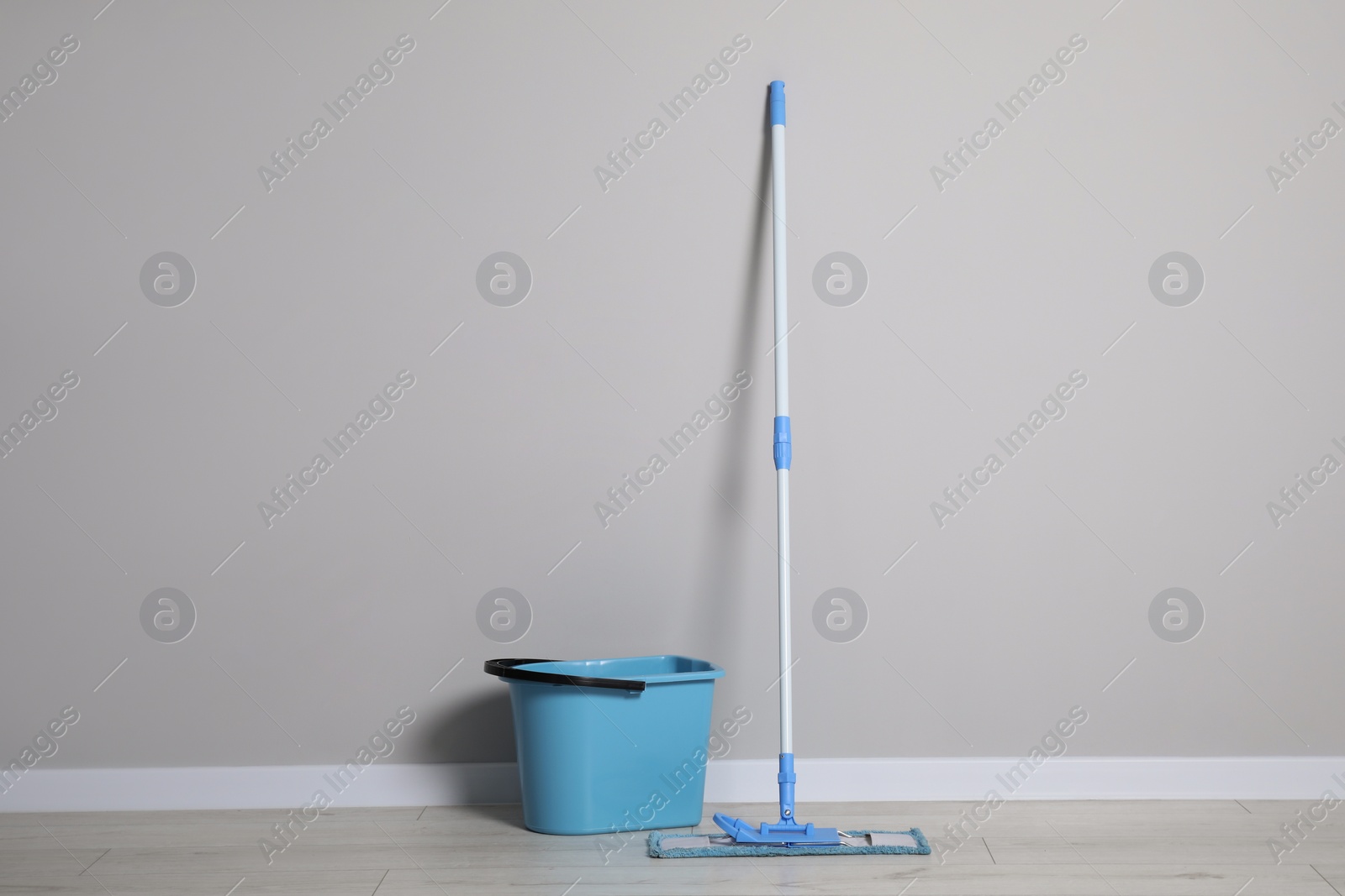 Photo of Mop and plastic bucket indoors. Cleaning floor