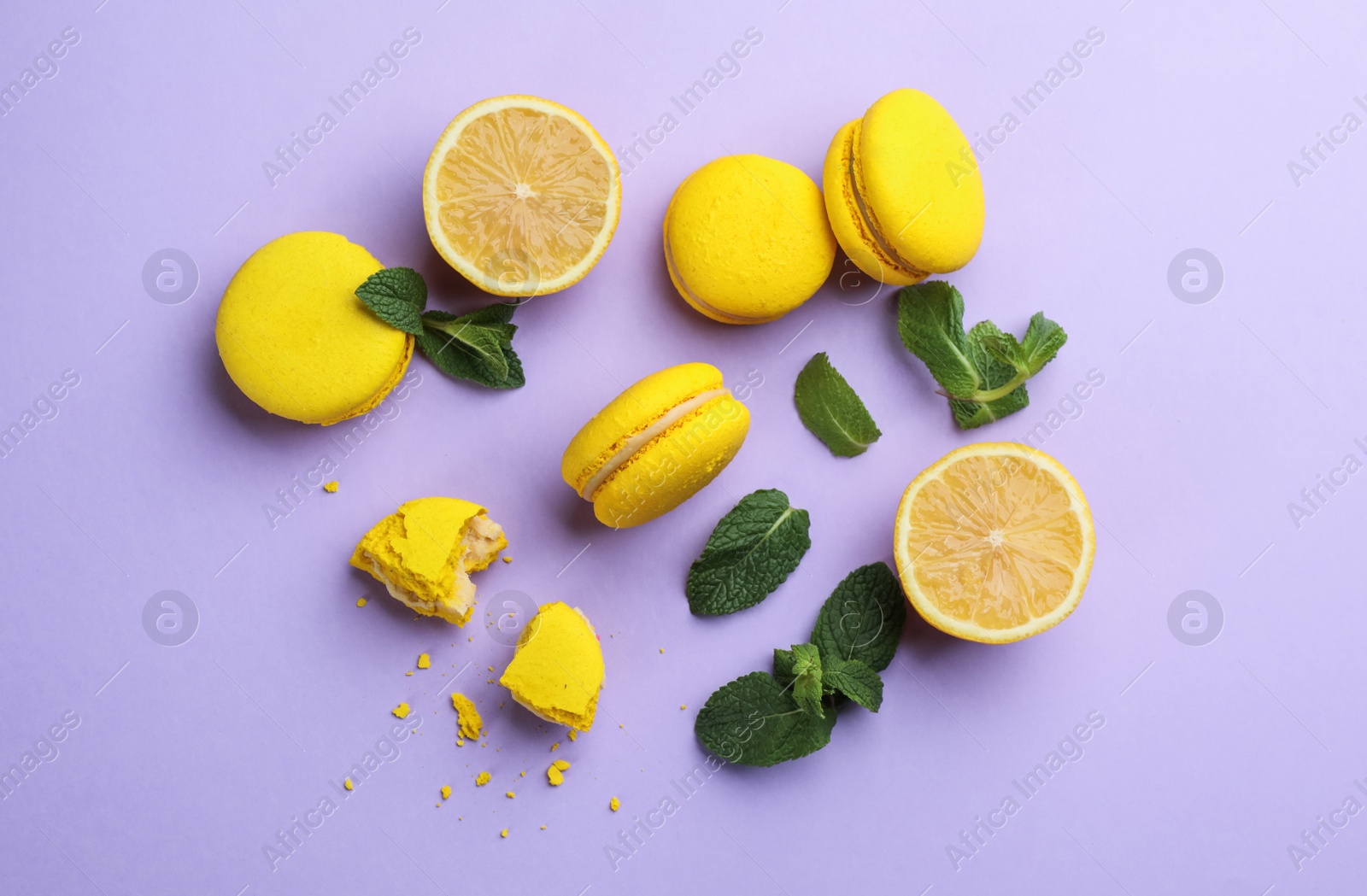 Photo of Flat lay composition with yellow macarons, mint and lemon on violet background