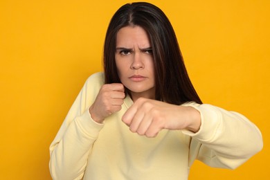 Photo of Young woman ready to fight on orange background