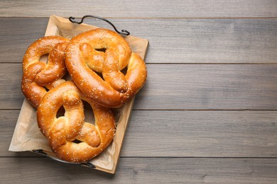 Tray with delicious pretzels on wooden table, top view. Space for text