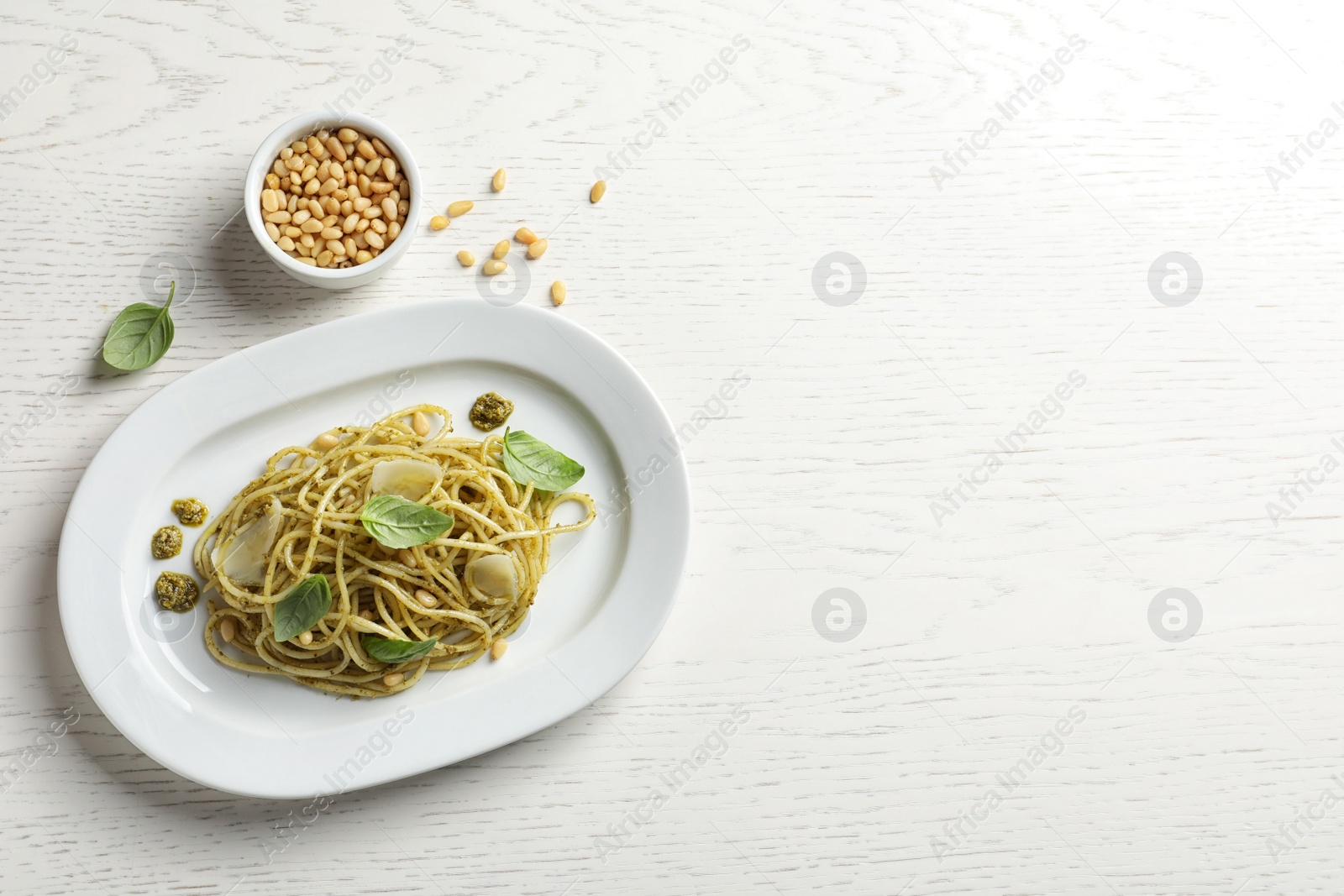 Photo of Flat lay composition with plate of delicious basil pesto pasta and space for text on wooden table