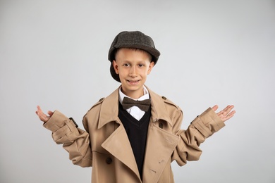 Photo of Cute little detective in hat and coat on grey background