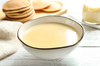 Bowl with condensed milk on wooden table. Dairy products