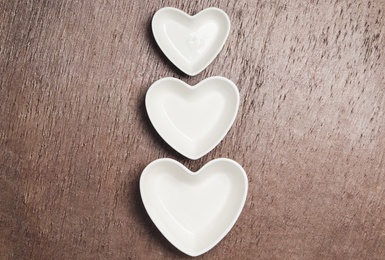 Heart shaped baking dishes on wooden table, flat lay. Cooking utensils