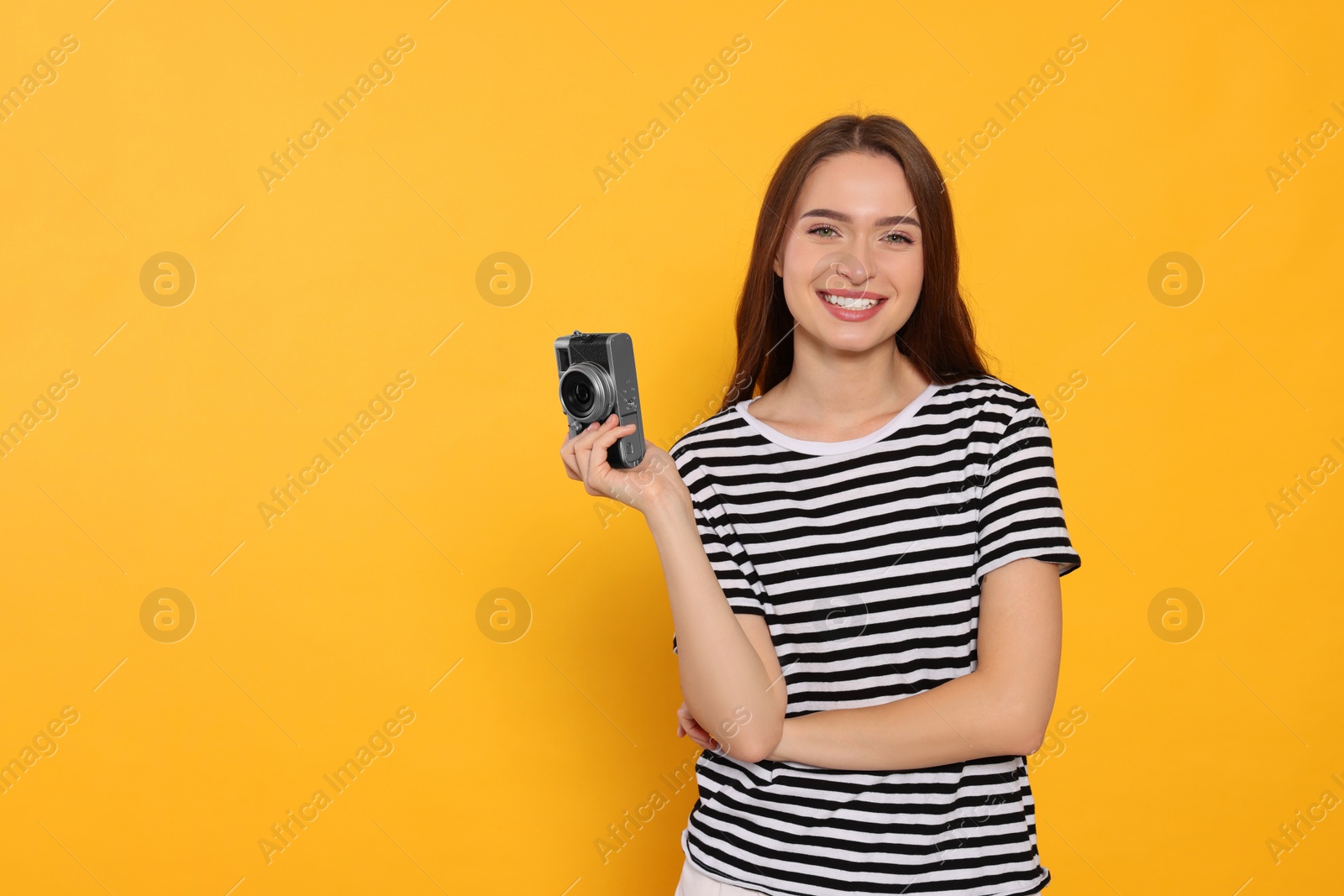 Photo of Young woman with camera on yellow background, space for text. Interesting hobby