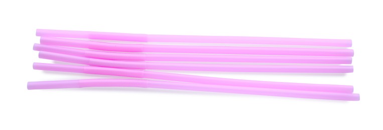 Photo of Light pink plastic cocktail straws on white background, top view