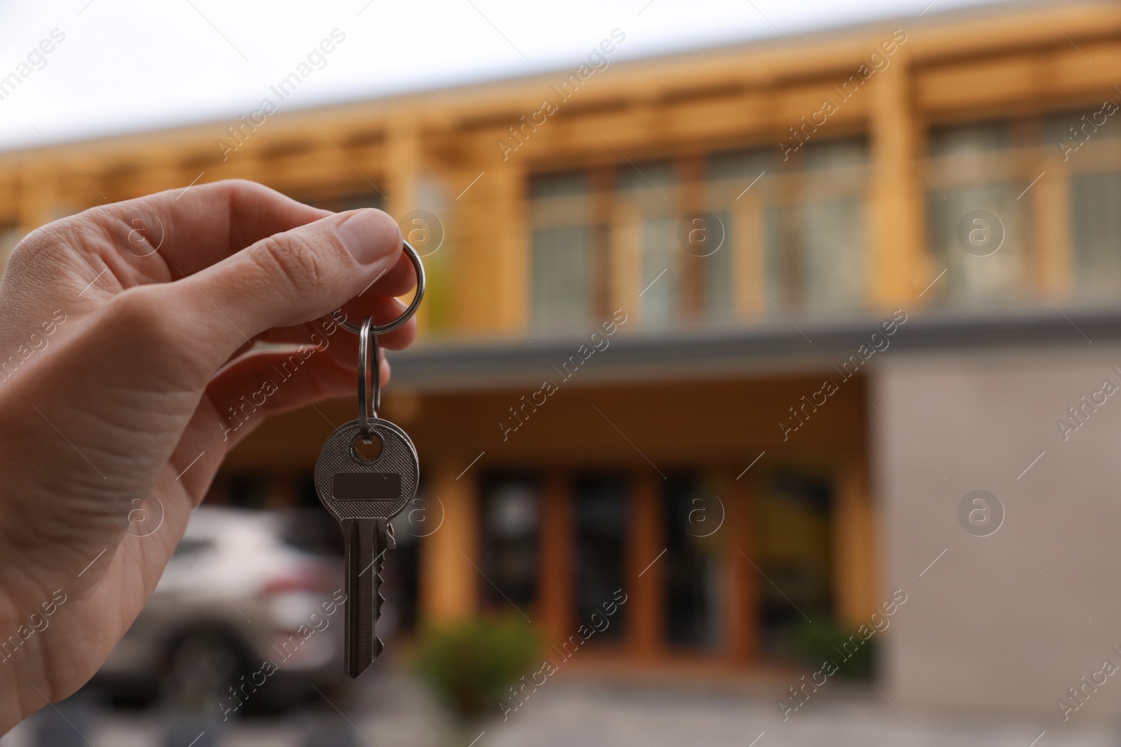 Photo of Real estate agent holding keys to new house outdoors, closeup. Space for text