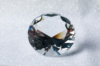 Photo of Beautiful dazzling diamond on shiny glitter background, closeup. Precious gemstone