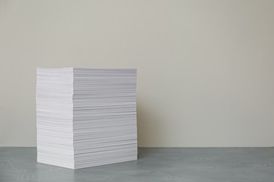 Photo of Stack of paper sheets on grey table. Space for text