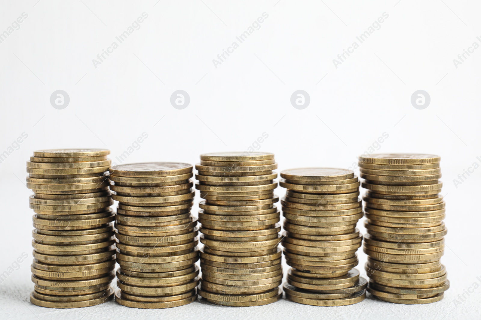 Photo of Many coins stacked on white table, space for text