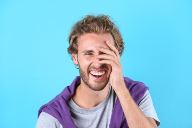 Photo of Handsome young man laughing on color background