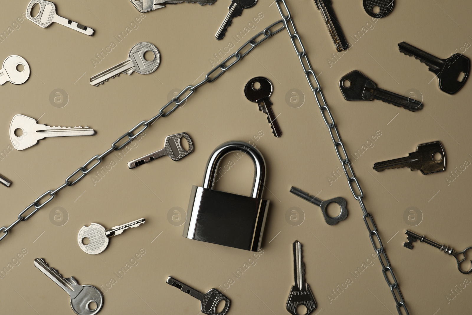Photo of Steel padlock, keys and chains on beige background, flat lay. Safety concept