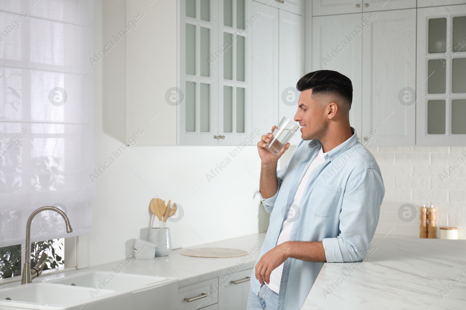 Photo of Man drinking tap water from glass in kitchen