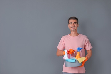 Man with cleaning supplies on color background