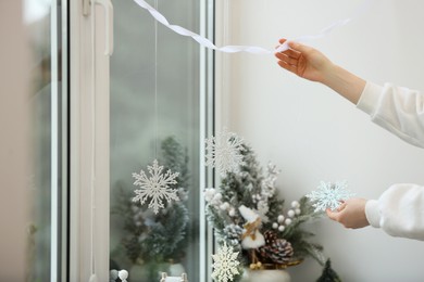 Photo of Woman decorating room for Christmas near window, closeup