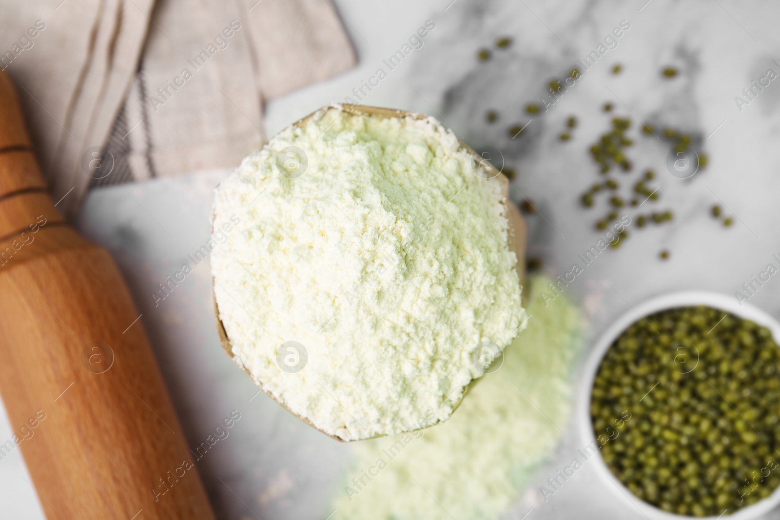 Photo of Mung bean flour in paper bag and seeds on white marble table, flat lay