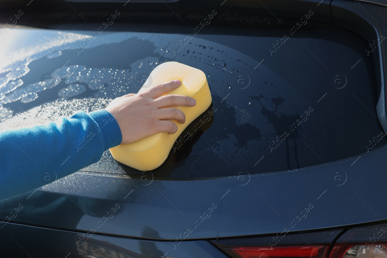 Photo of Man washing car with sponge outdoors, closeup