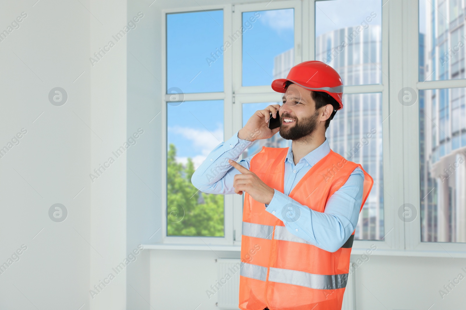 Photo of Man in reflective uniform talking on phone indoors, space for text