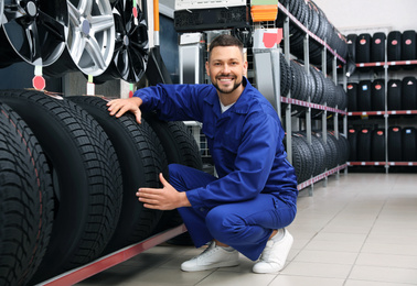 Photo of Male mechanic with car tires in auto store